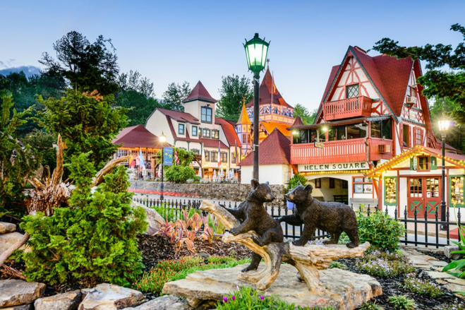 Town park with a sculpture of baby bears playing in the woods against a backdrop of bavarian style buildings.